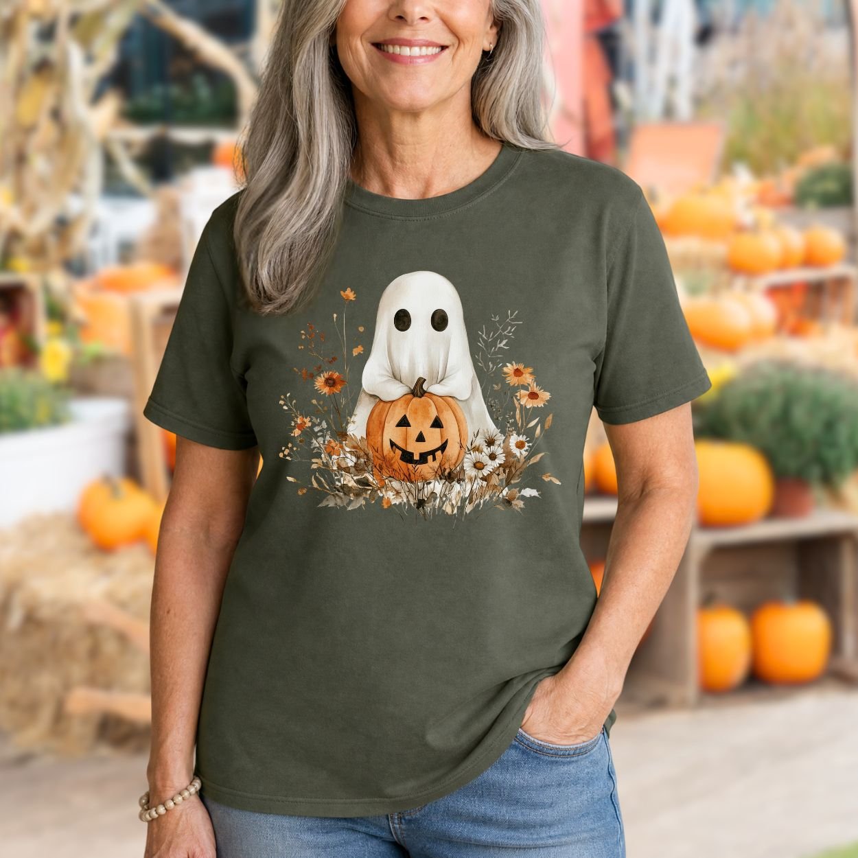 Woman in an olive green Halloween Boho Ghost t-shirt with a jack o'lantern and autumn florals.