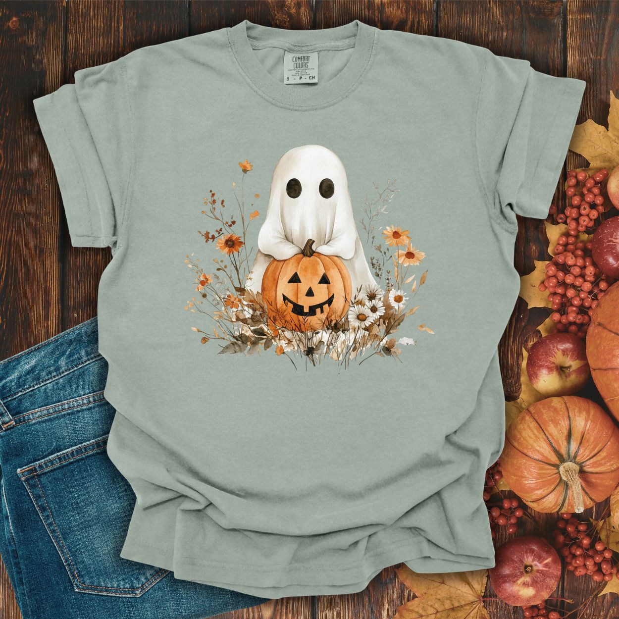 Bay-colored, relaxed-fit cotton t-shirt with a boho ghost holding a jack-o'-lantern amidst autumn florals.