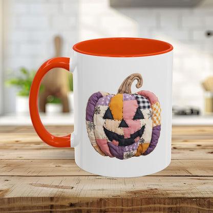 White ceramic mug with orange handle and interior, featuring a quilted patchwork jack-o'-lantern design.