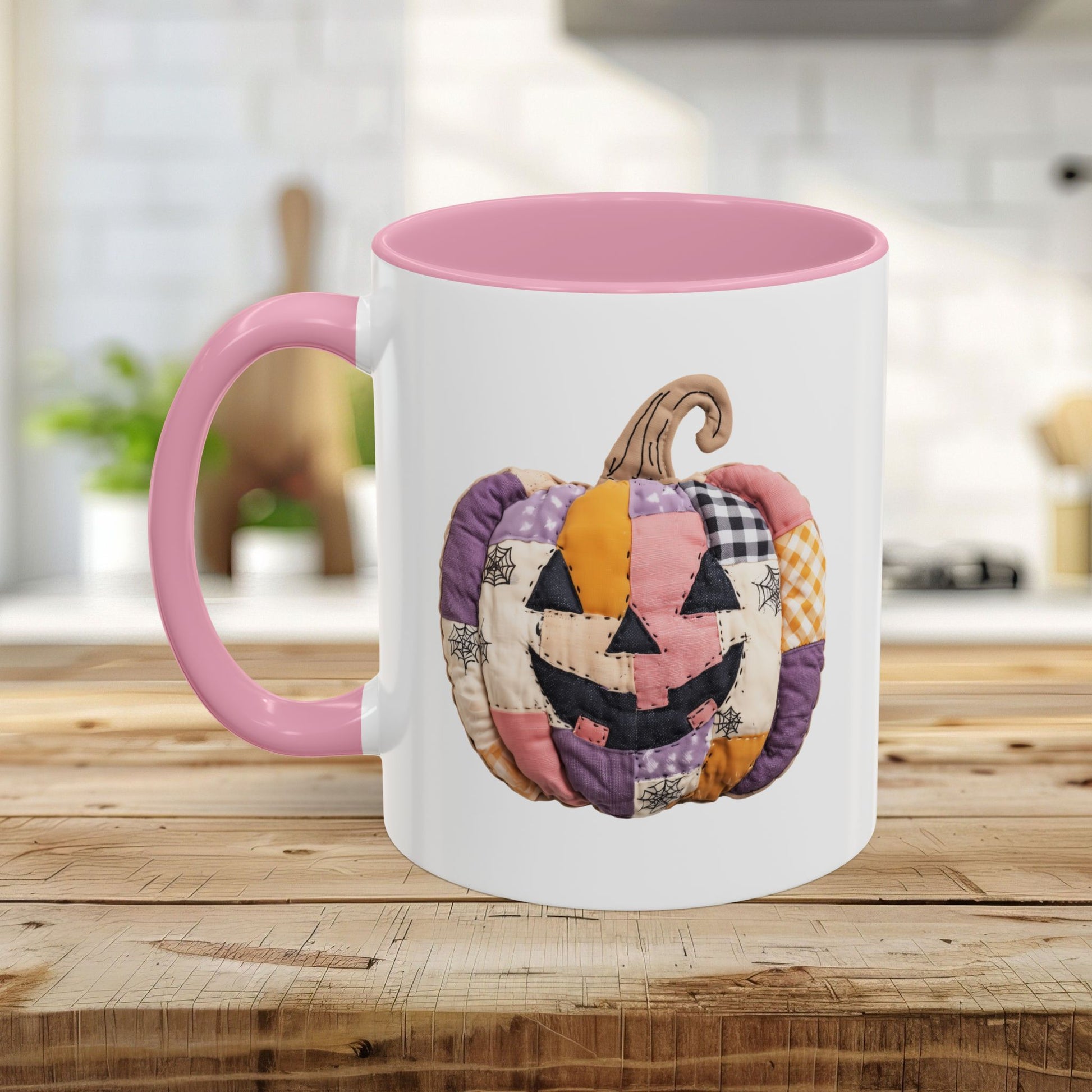 White ceramic mug with pink handle and interior, featuring a colorful quilted jack-o'-lantern design.