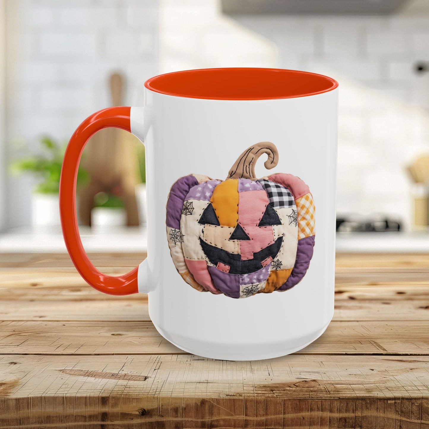 White ceramic mug with orange handle and interior, featuring a colorful quilted patchwork jack-o'-lantern design.
