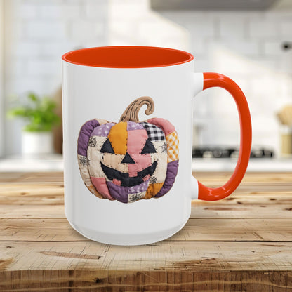 White ceramic mug with orange handle and interior, featuring a quilted patchwork jack-o'-lantern design.