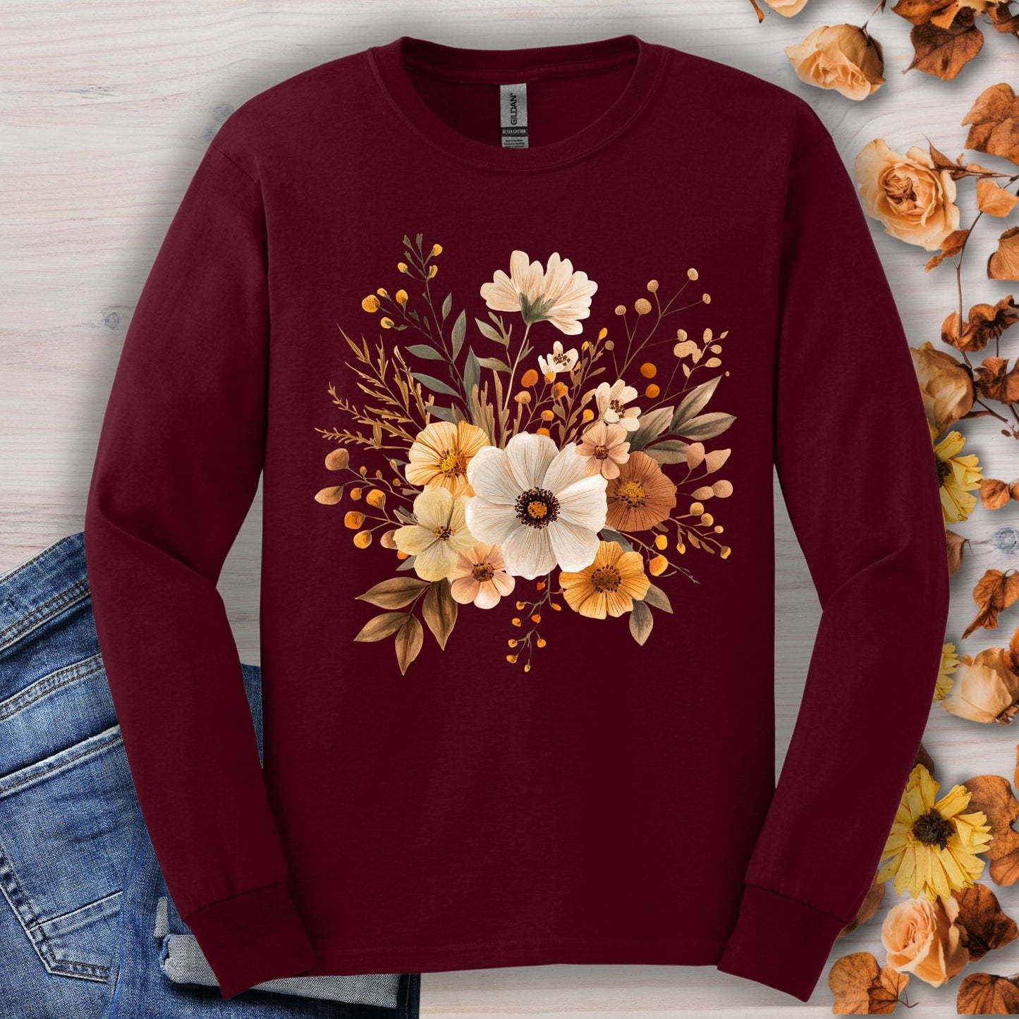 Maroon long-sleeve cotton tee with a cottagecore design of muted autumn flowers, shown with jeans.