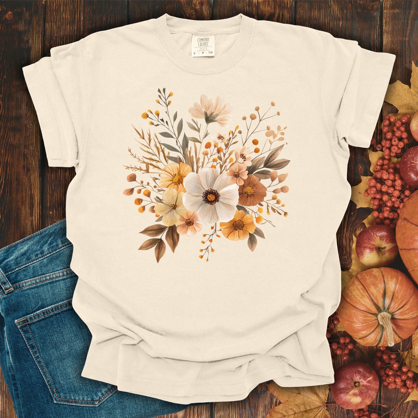 Ivory Harvest Blooms T-Shirt with autumn-hued floral graphic, shown with denim and fall decor.