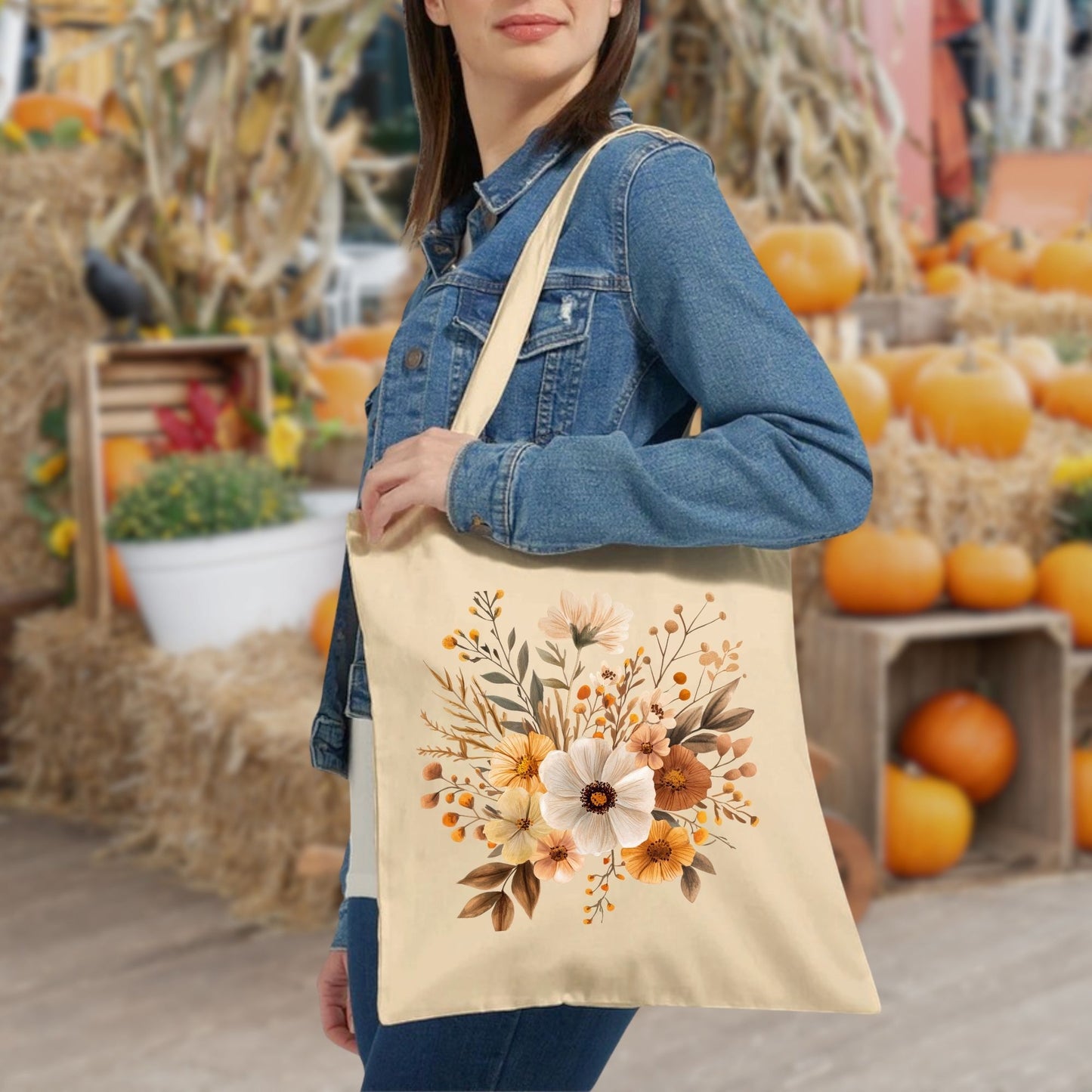Woman wearing a denim jacket, carrying a cream cotton canvas tote bag with watercolor autumnal flower design.