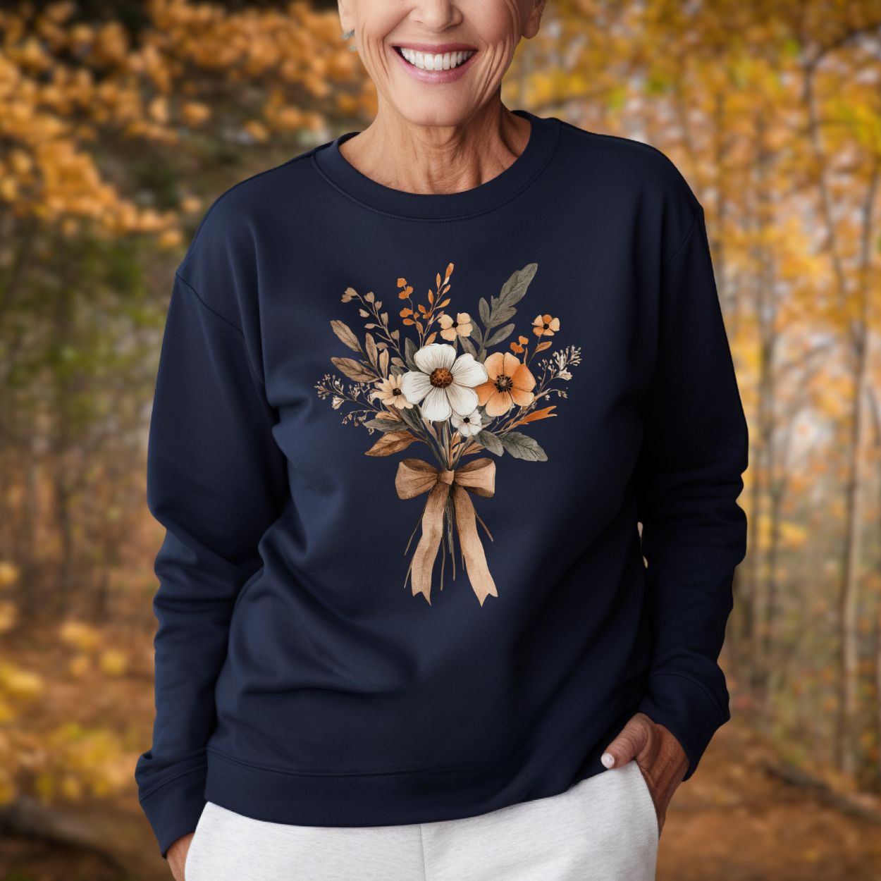 Woman in a navy sweatshirt with a watercolor autumn floral bouquet and light brown bow.