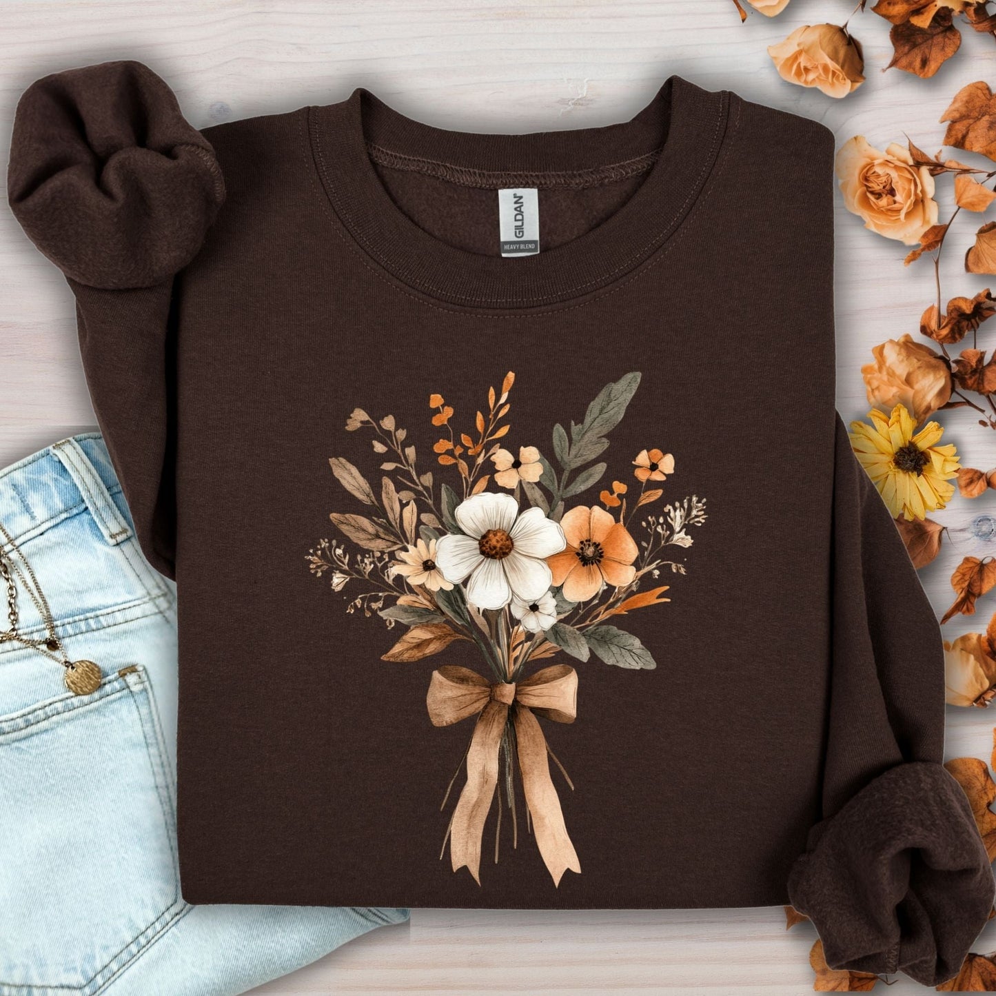 Dark chocolate sweatshirt with a watercolor harvest bouquet of white, orange, and brown flowers tied with a bow.