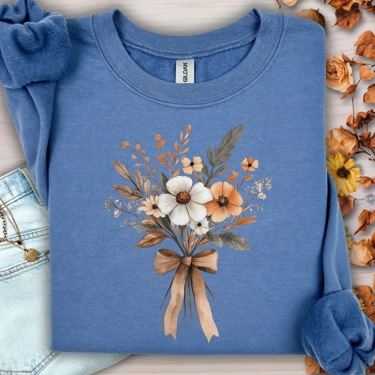 Indigo blue sweatshirt with a watercolor-inspired harvest floral bouquet tied with a brown bow.