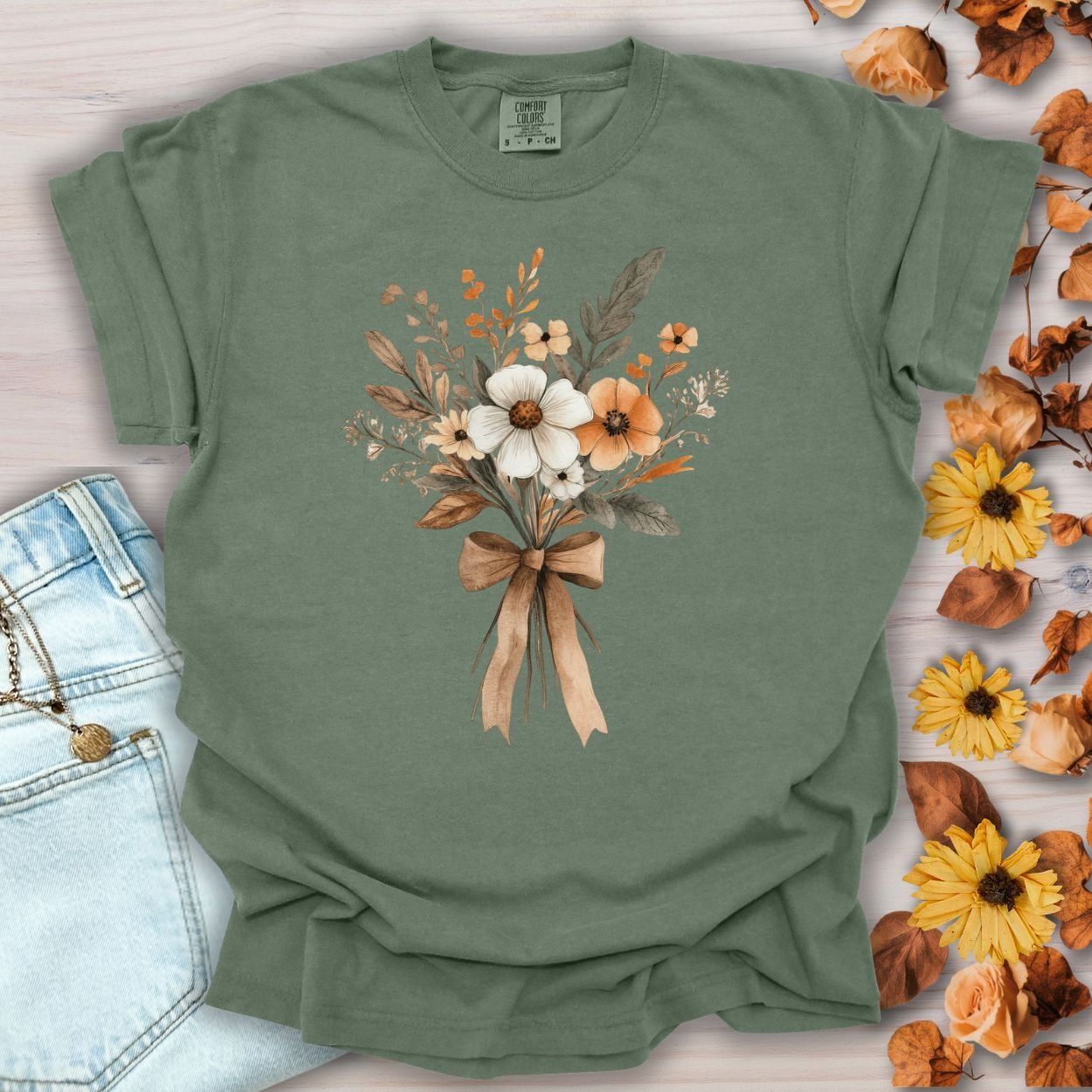 Moss green relaxed-fit t-shirt with a watercolor harvest bouquet design and a brown bow.
