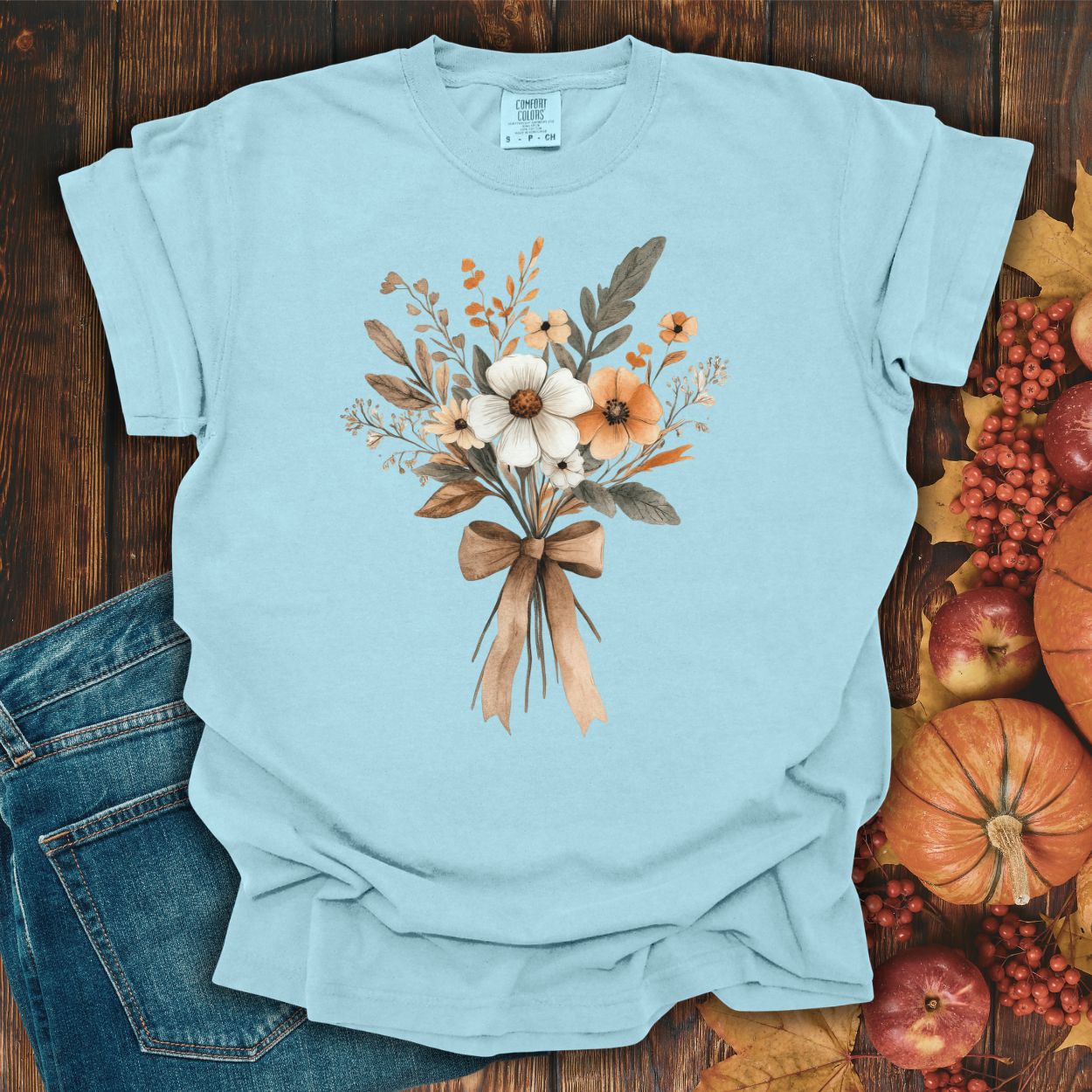 Chambray Harvest Bouquet T-Shirt with watercolor fall flowers and a brown bow, styled with jeans and autumn decor.