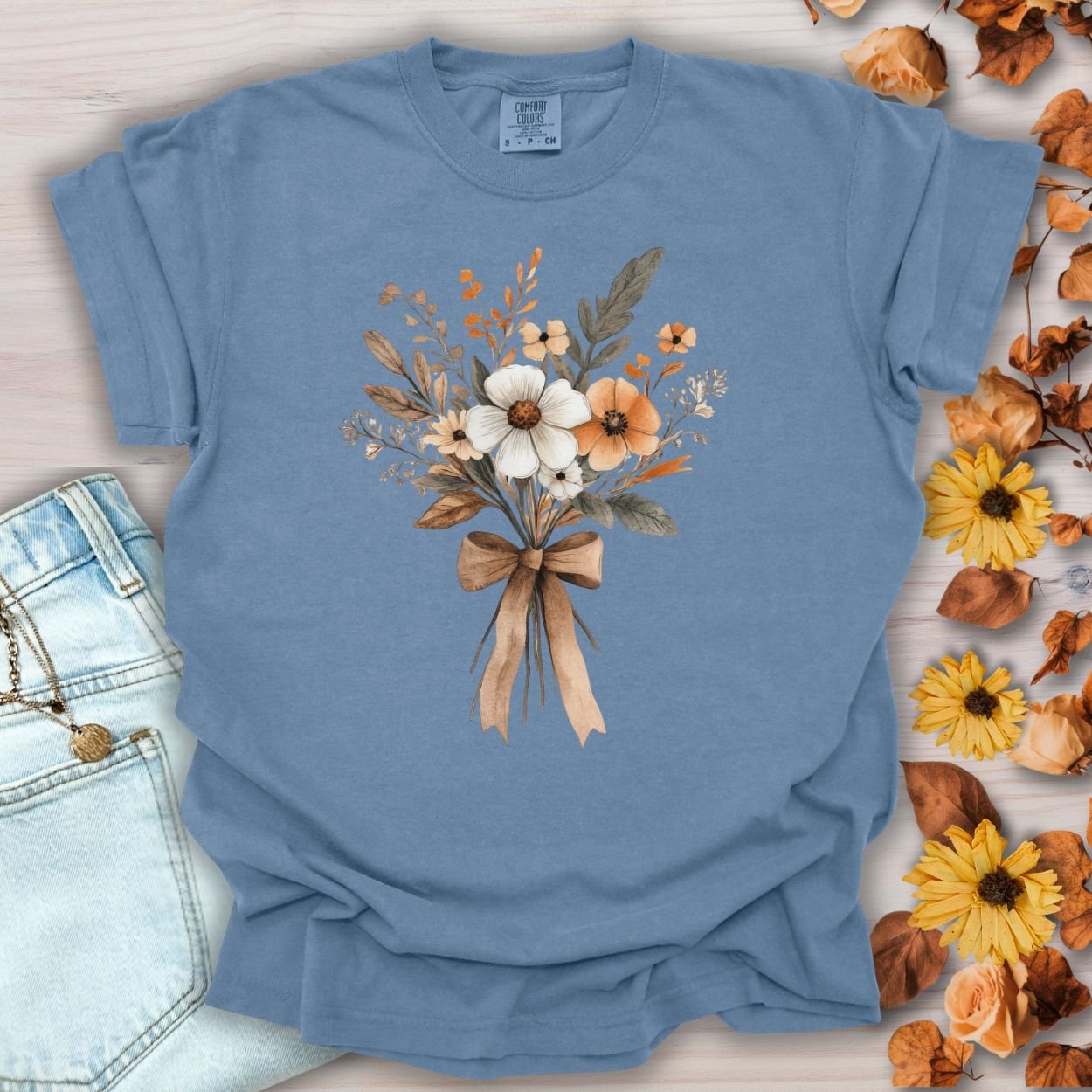 Blue Jean Harvest Bouquet T-Shirt with watercolor fall flowers and a brown bow, made from 100% USA-grown cotton.