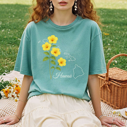 Garment-dyed teal t-shirt with yellow hibiscus flowers and a white outline of the Hawaiian islands.