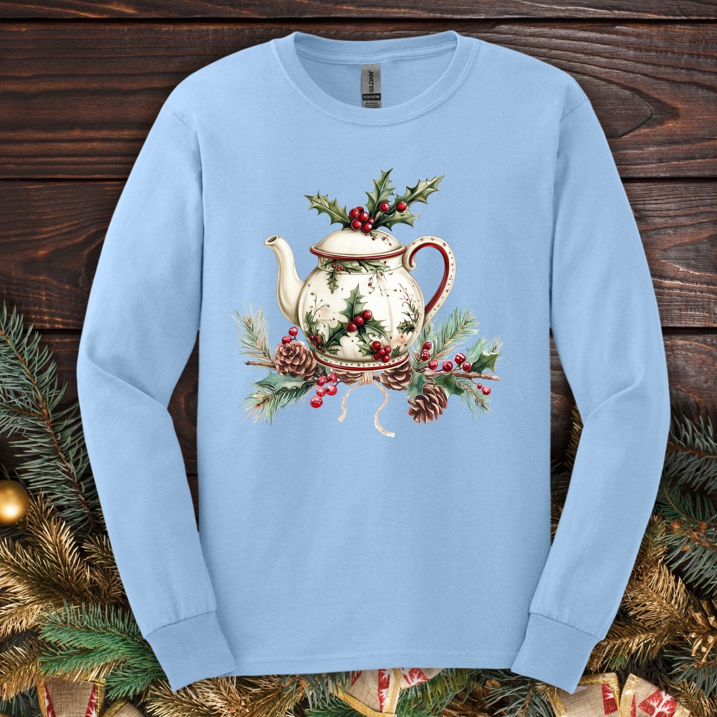 Light blue long-sleeve tee with a watercolor Christmas teapot, holly, and pinecone design.