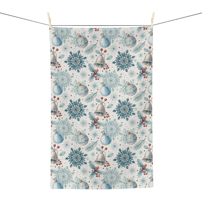 Microfiber tea towel with a muted blue and silver holiday pattern of bells, snowflakes, and berries.