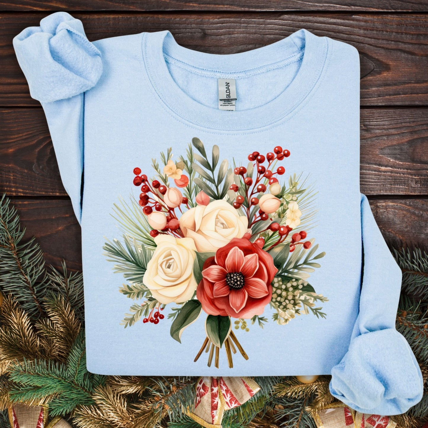 Light blue Gildan sweatshirt with a watercolor Christmas bouquet of red, cream, and green flowers and holly.
