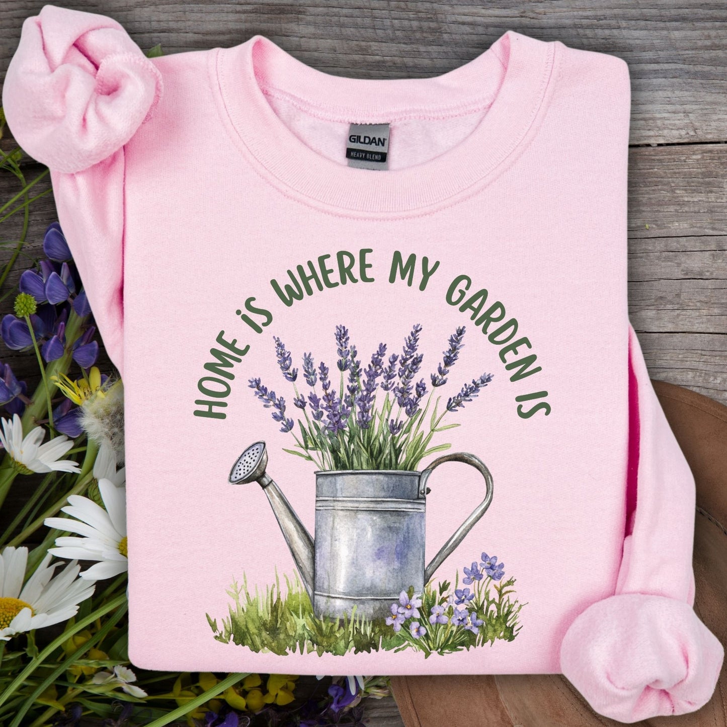 Light pink unisex sweatshirt with "Home is where my garden is" text and a watercolor watering can with lavender.