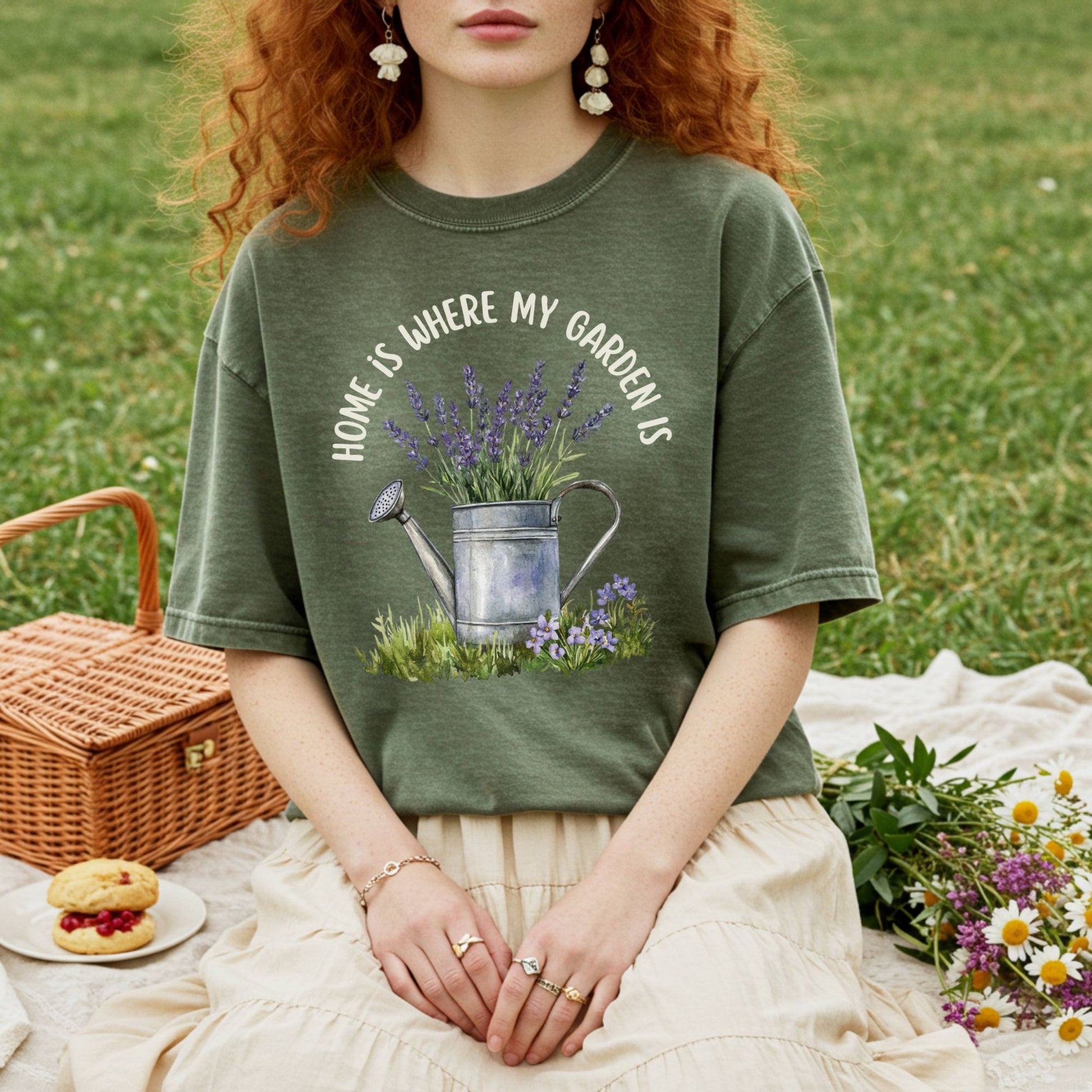Garment-dyed olive green t-shirt with "Home Is Where My Garden Is" text and a watercolor watering can with lavender.