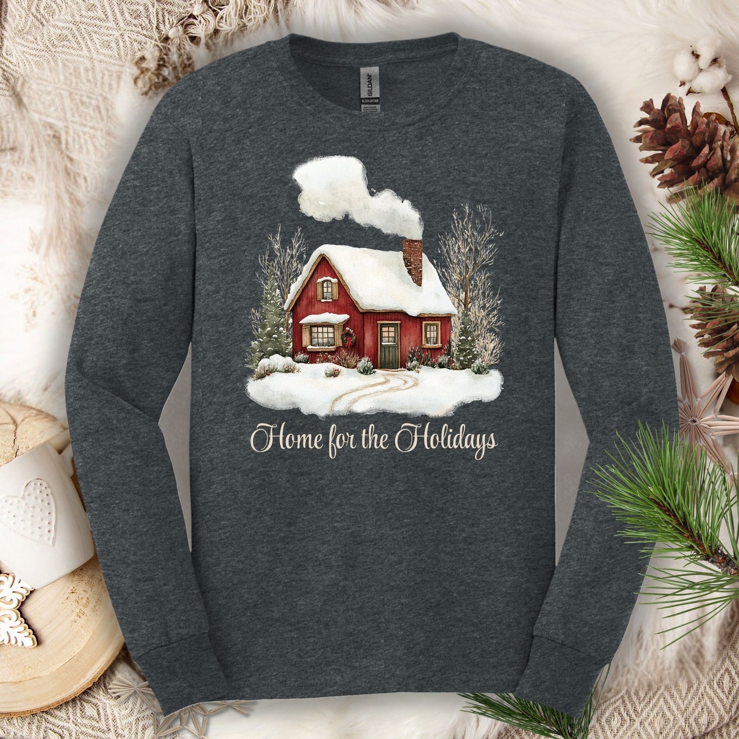 Dark Heather long sleeve tee with a watercolor red winter cabin, evergreens, and "Home for the Holidays" script.
