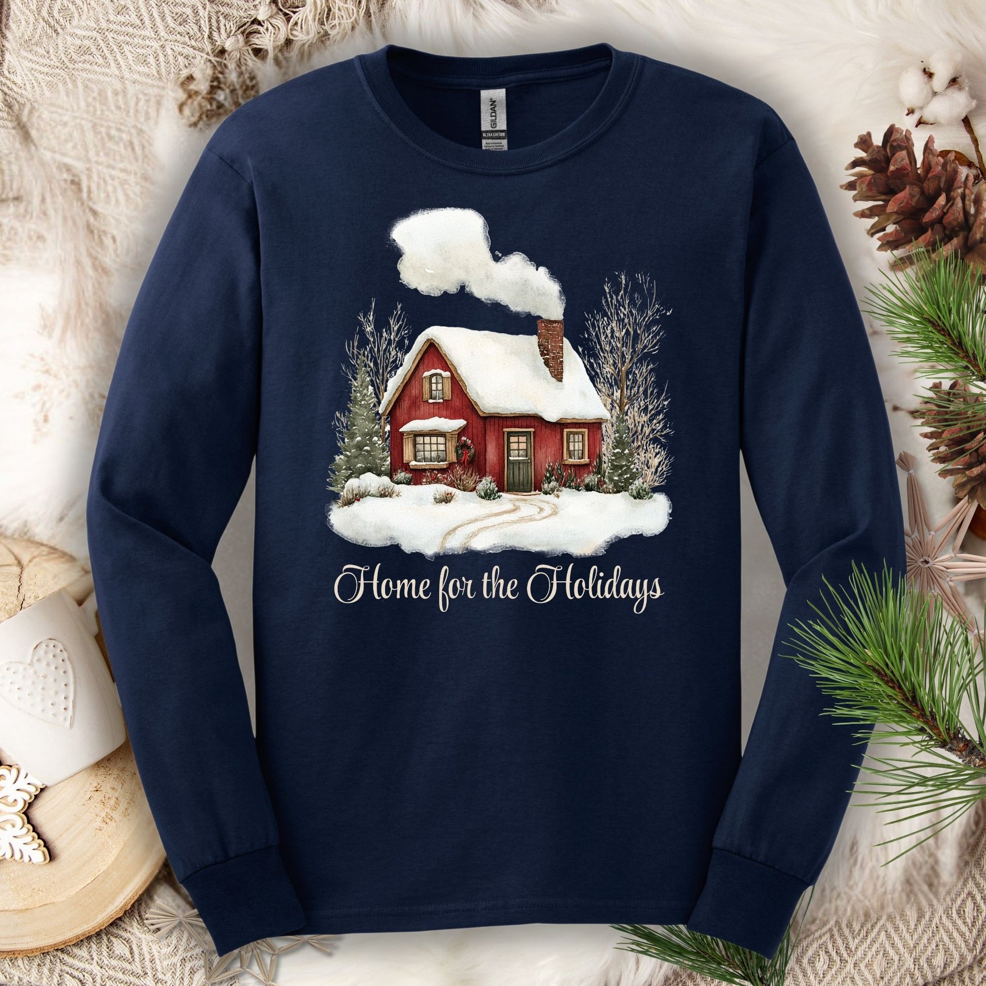 Navy long sleeve tee with a watercolor red winter cabin, evergreens, and "Home for the Holidays" script.