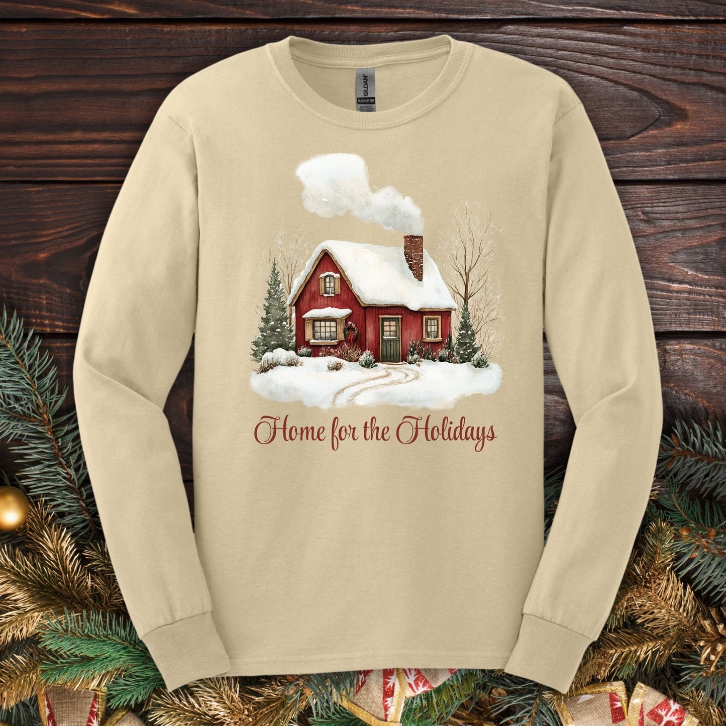 Sand Gildan Softstyle long sleeve tee with watercolor red cabin, evergreens, and "Home for the Holidays" script.
