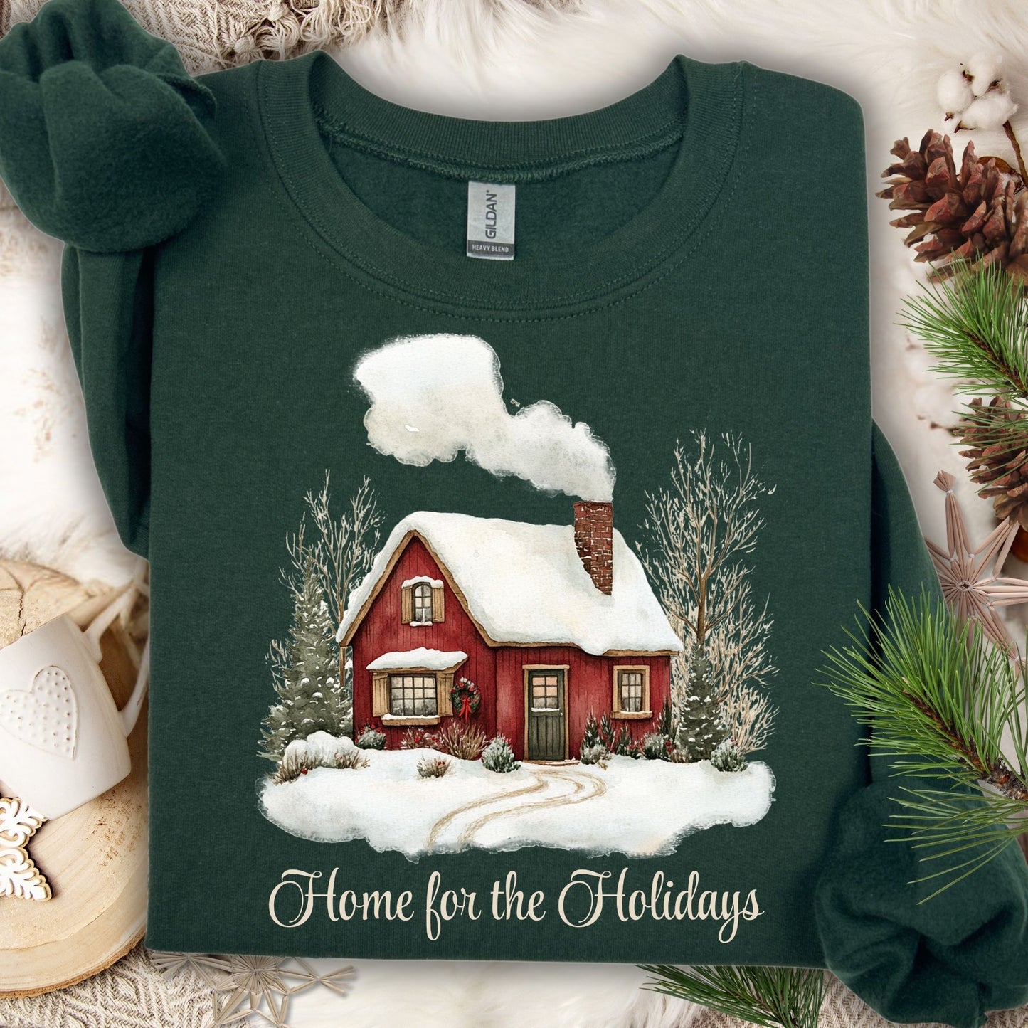 Forest Green Gildan sweatshirt with a vintage watercolor red cabin in snow and "Home for the Holidays" text.