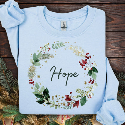 Light blue Gildan sweatshirt with a watercolor Christmas wreath and "Hope" text, surrounded by greenery and red berries.