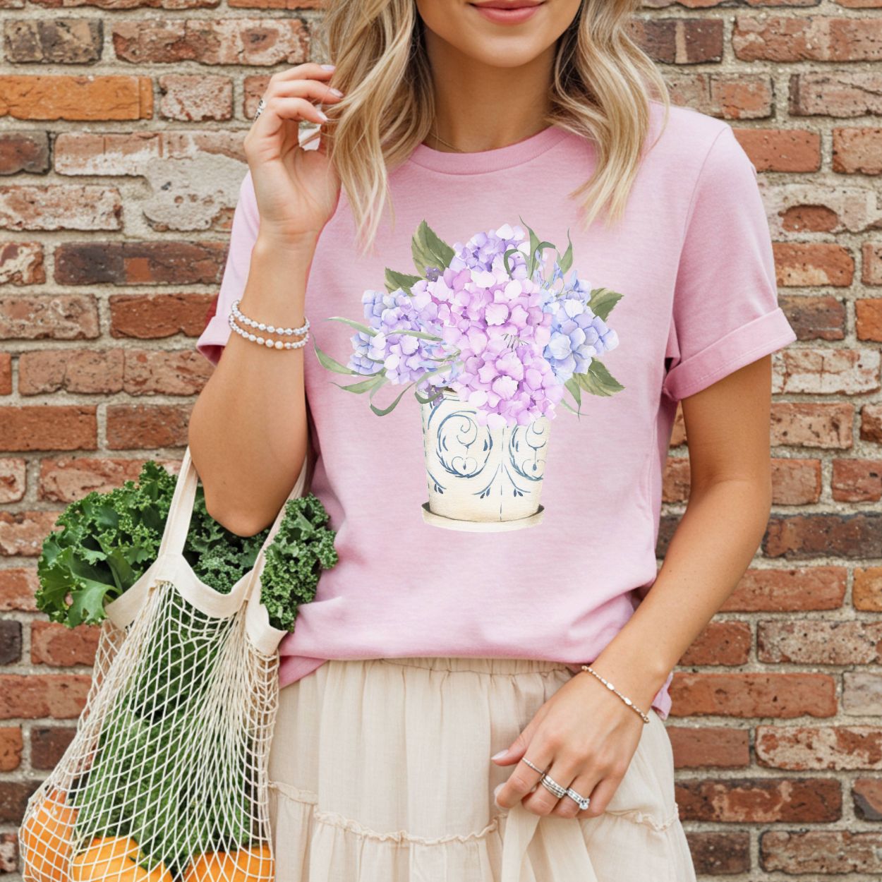 Pink garment-dyed t-shirt with a watercolor-style hydrangea bouquet in a vintage ceramic vase.