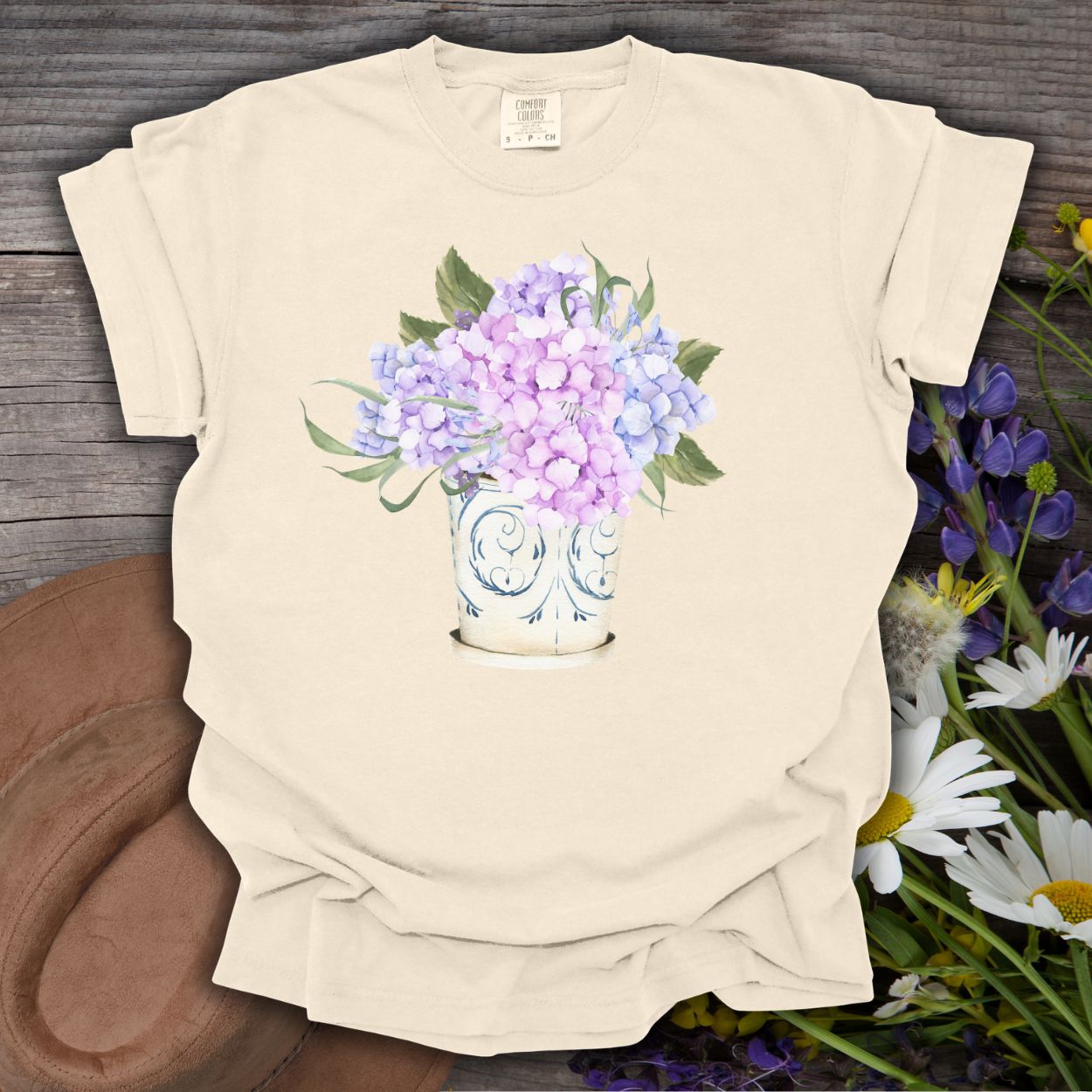 Ivory S t-shirt with a watercolor-style lilac and pale blue hydrangea bouquet in a vintage ceramic vase.