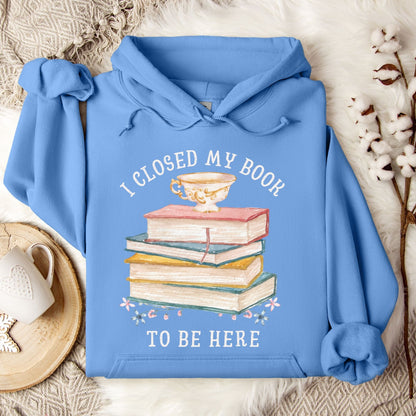 Carolina Blue Gildan 18500 hoodie with "I Closed My Book To Be Here" text and a stack of books graphic.