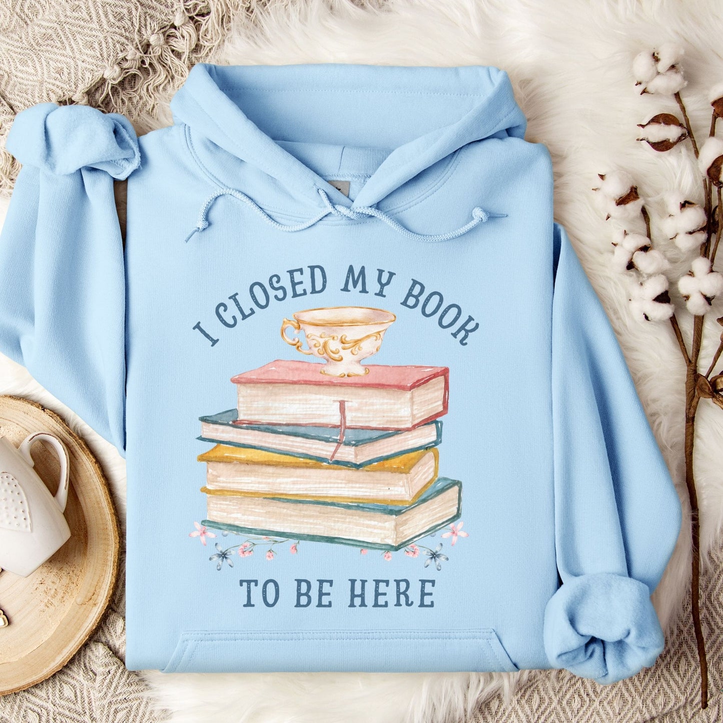 Light blue Gildan 18500 hoodie with "I Closed My Book To Be Here" text and stacked books graphic.