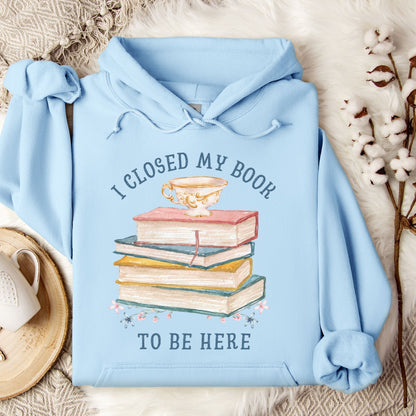 Light blue Gildan 18500 hoodie with "I Closed My Book To Be Here" text and stacked books graphic.