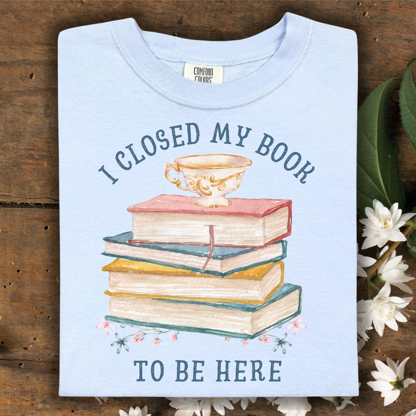 Hydrangea blue "I Closed My Book To Be Here" t-shirt with watercolor books, teacup, and floral design.