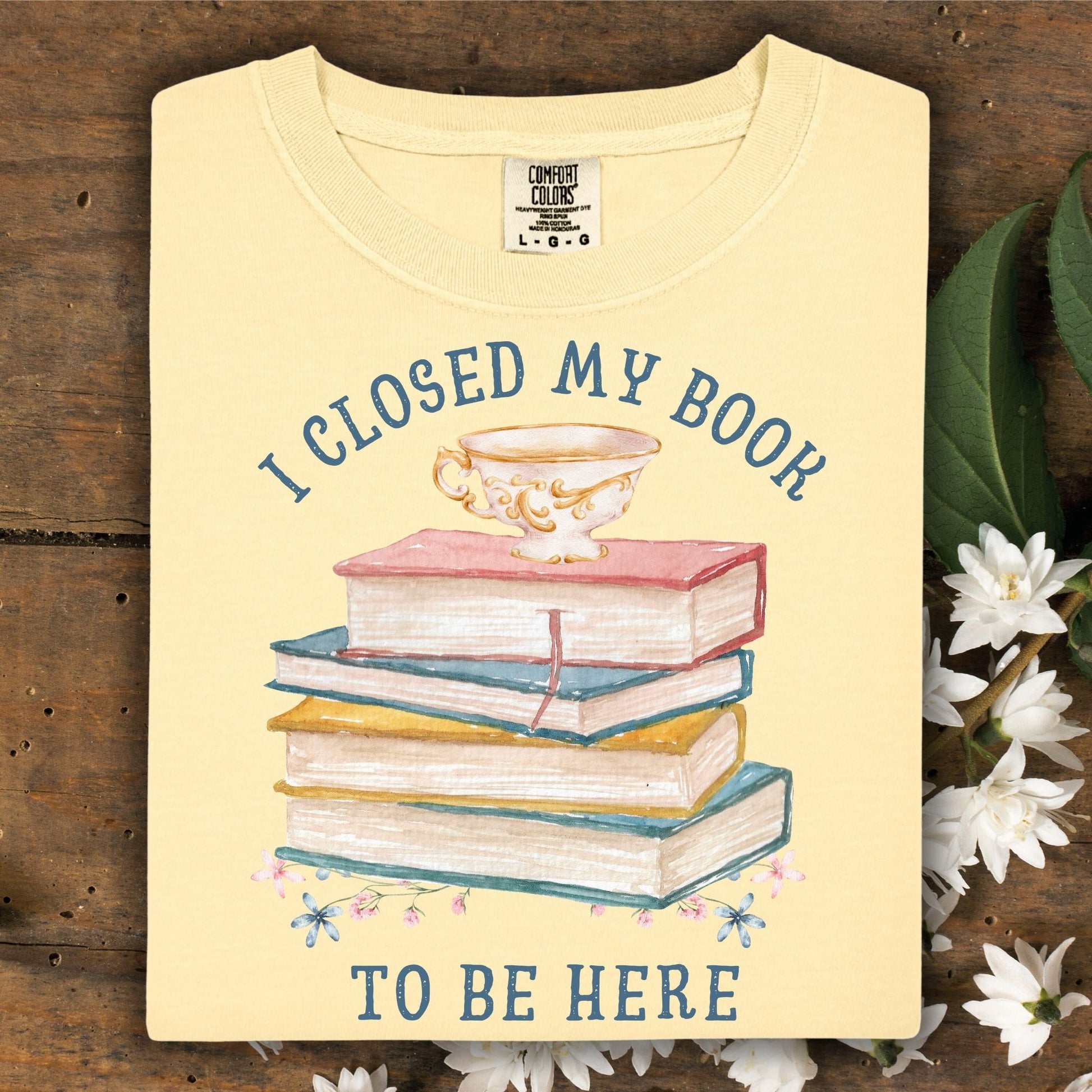 Butter Comfort Colors tee with "I Closed My Book To Be Here" and watercolor books, teacup, and florals.