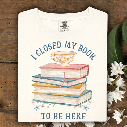 Ivory "I Closed My Book To Be Here" t-shirt with watercolor books, teacup, and florals.