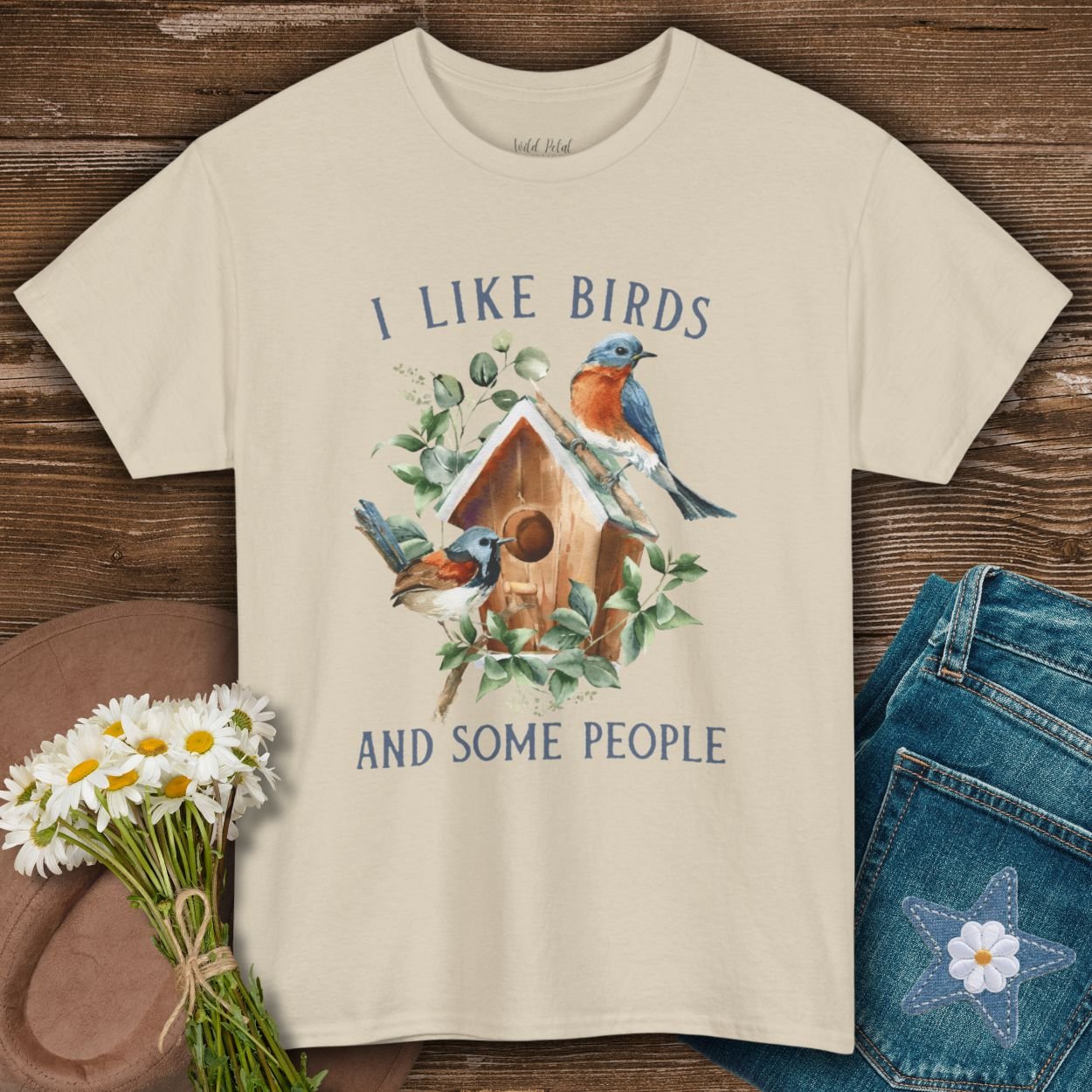 Sand S cotton t-shirt with "I like birds and some people" text and watercolor bluebirds on a birdhouse.