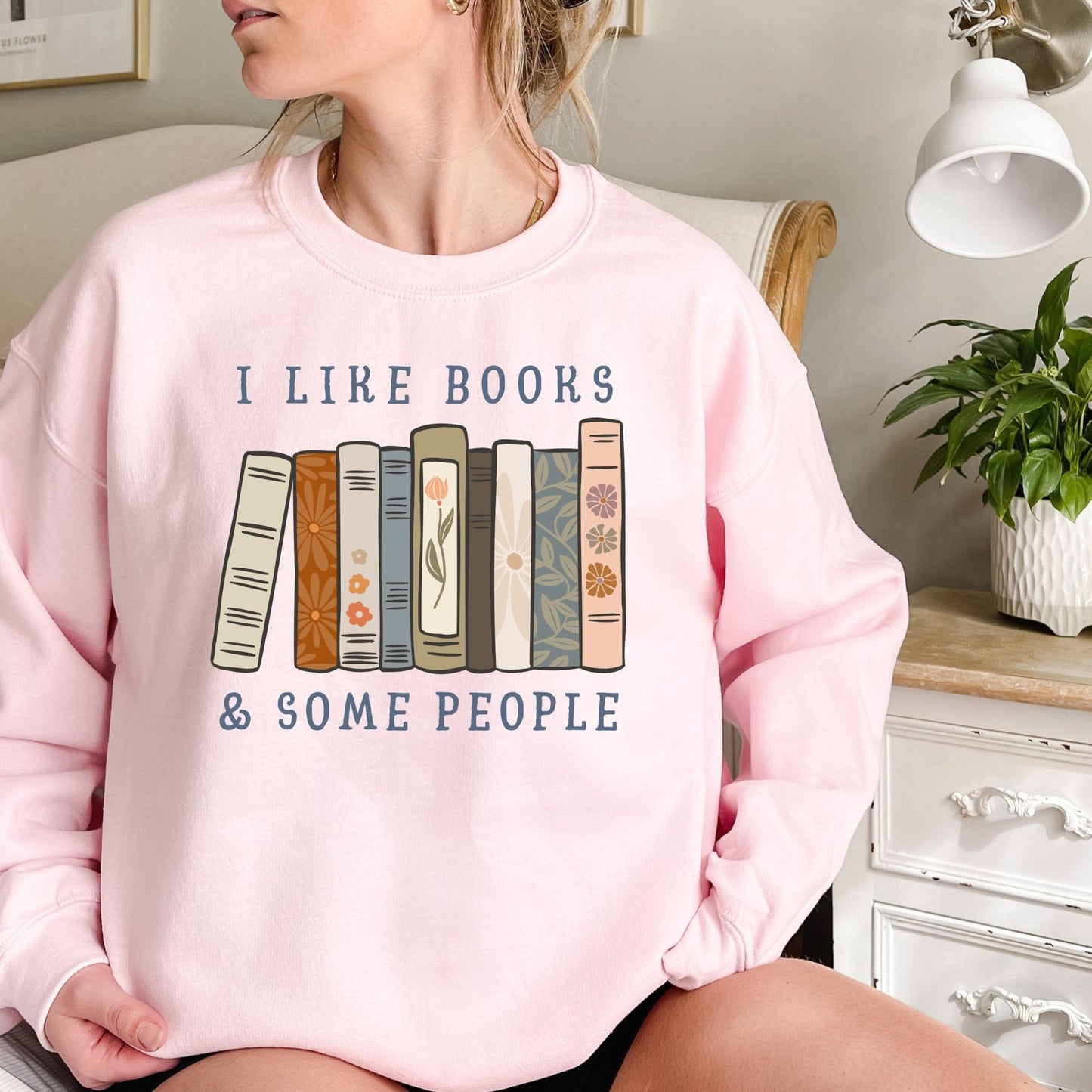 Pink Gildan crewneck sweatshirt with "I like books & some people" and a row of vintage books graphic.