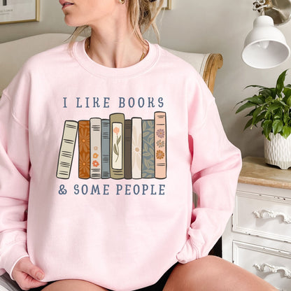 Pink Gildan crewneck sweatshirt with "I like books & some people" and a row of vintage books graphic.