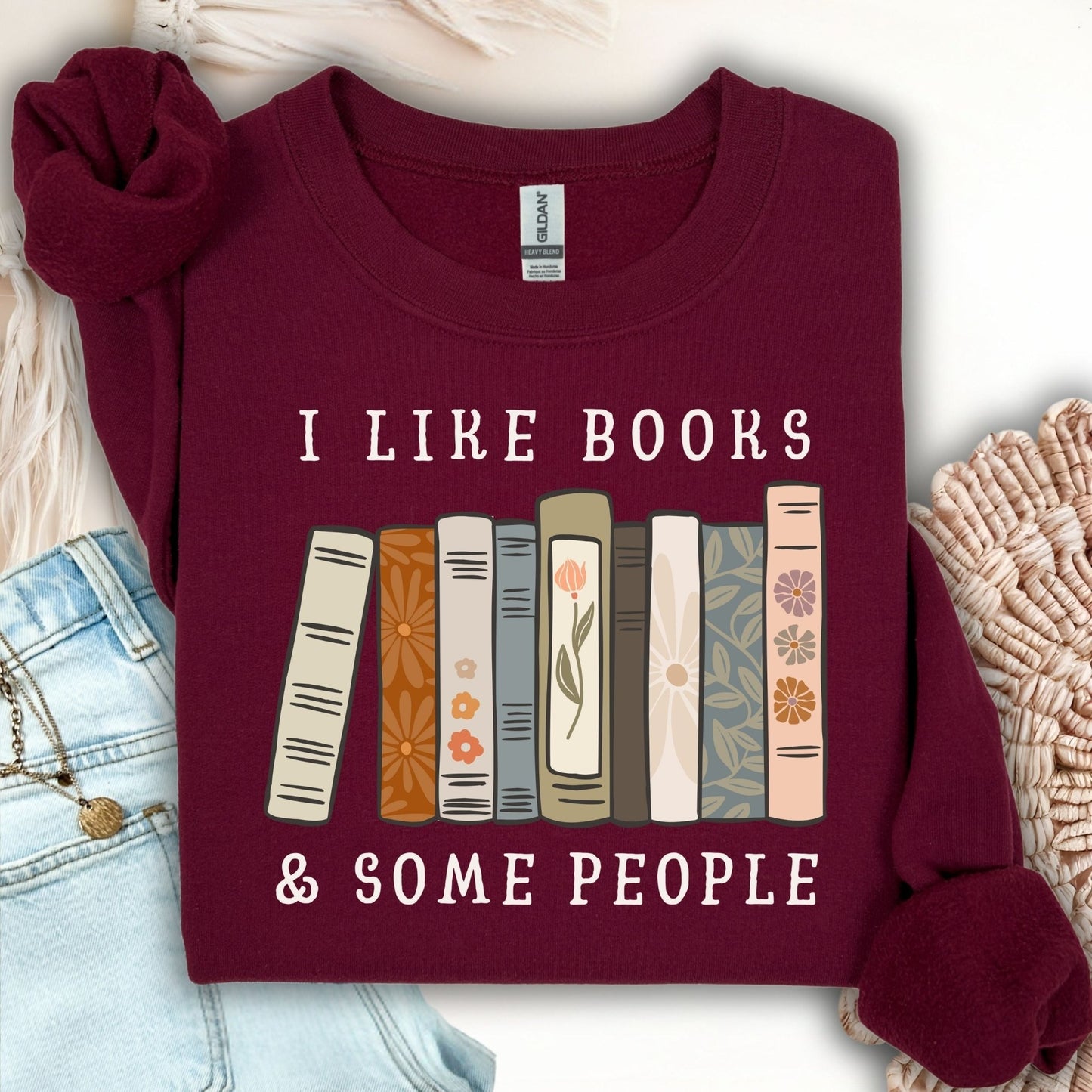 Maroon Gildan crewneck sweatshirt with "I like books & some people" and a row of vintage books graphic.
