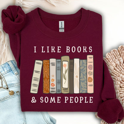 Maroon Gildan crewneck sweatshirt with "I like books & some people" and a row of vintage books graphic.