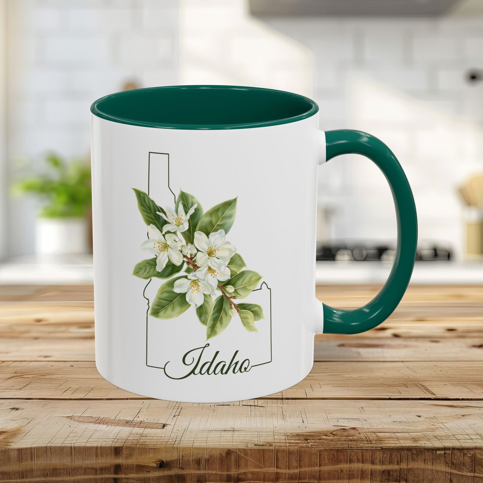 11oz white ceramic mug with green handle and interior, featuring Idaho state outline and Syringa flower art.