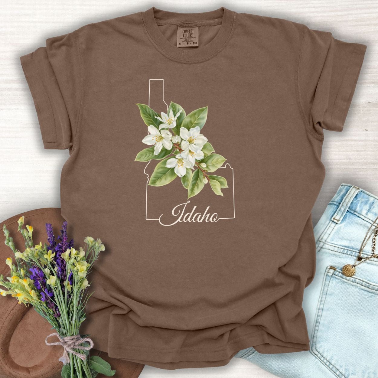 Espresso garment-dyed cotton t-shirt with Idaho outline, Syringa blossoms, and "Idaho" script.