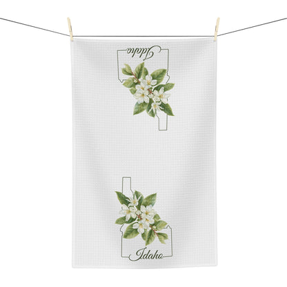 White microfiber tea towel with Idaho state outline and Syringa (mock orange) blossoms.