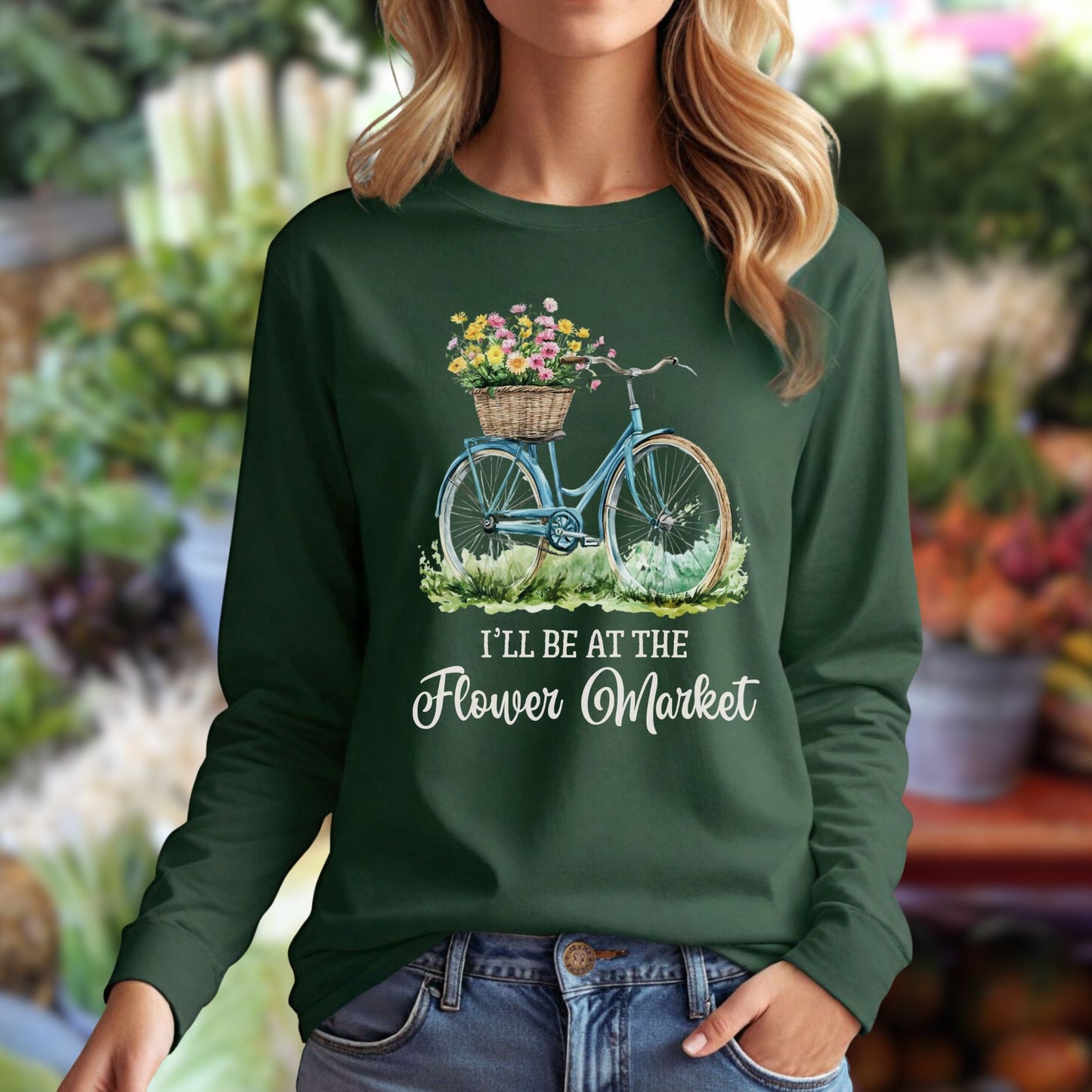 Woman in a dark green long-sleeve tee with a vintage bicycle and flower basket graphic, "I'll Be At The Flower Market" text.