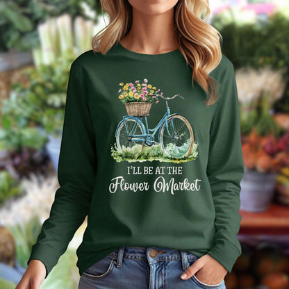 Woman in a dark green long-sleeve tee with a vintage bicycle and flower basket graphic, "I'll Be At The Flower Market" text.
