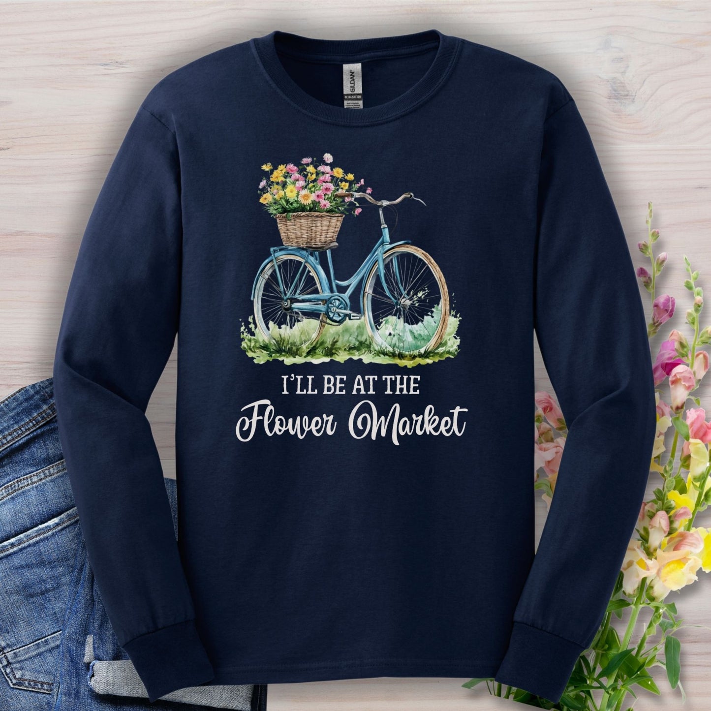 Navy long sleeve tee with a hand-painted bicycle and pastel flower basket, "I'll Be At The Flower Market" text.