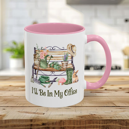 Pink 11oz ceramic gardener mug with "I'll Be In My Office" and watercolor garden tools, bench, and bunny.