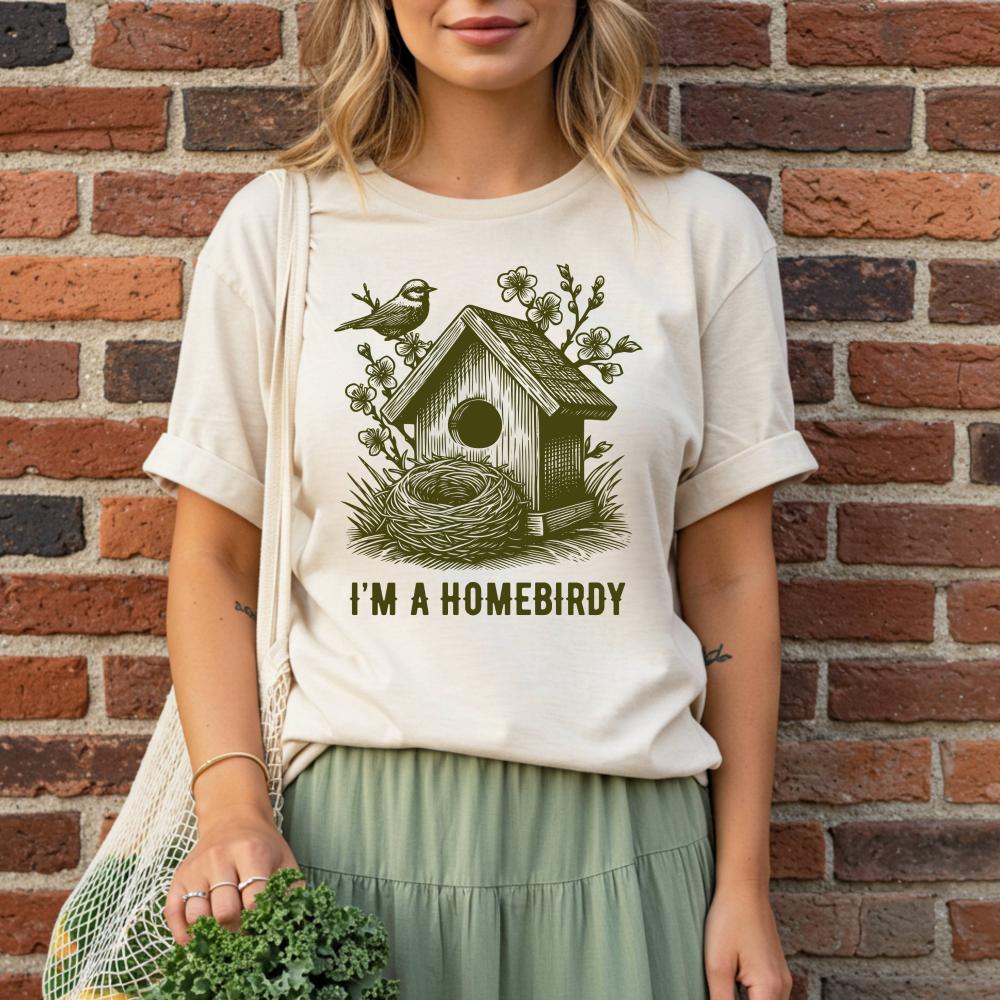 young woman wearing a t-shirt with a birdhouse design and text against a brick wall.