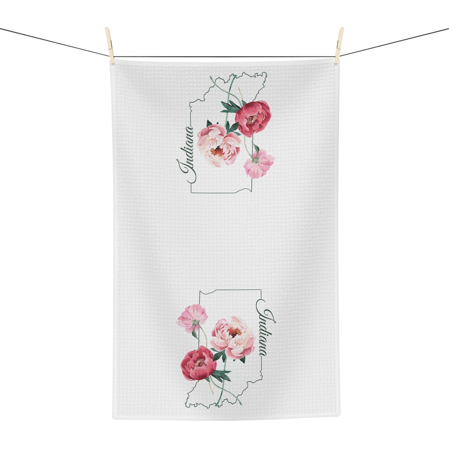 White microfiber tea towel with pink peony design inside an Indiana state outline, hanging on a clothesline.