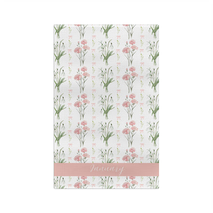 White microfiber tea towel with watercolor pink carnations, snowdrops, and "January" on a pink band.