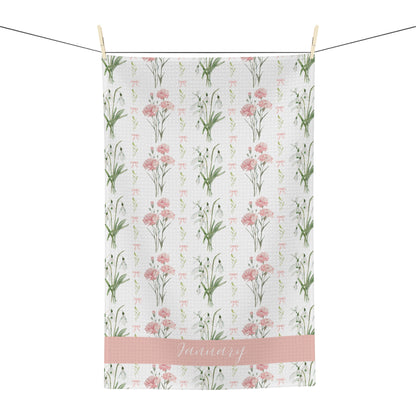 White microfiber tea towel with pink carnations, snowdrops, and "January" script, hanging on a line.